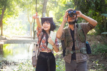 Family with father and daughter tourist backpack hiking doing activity while father looking binoculars in holiday together, man and teenager woman journey adventure trip and looking map.