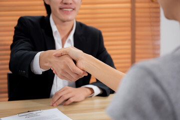 Young asian businessman talking and negotiation about agreement while congratulating with businesswoman with handshake, job interview, man shake hands with partner woman, business concept.