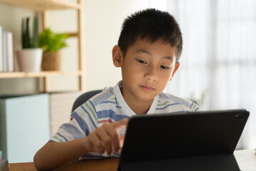 Asian boy is studying online via the internet on tablet at home