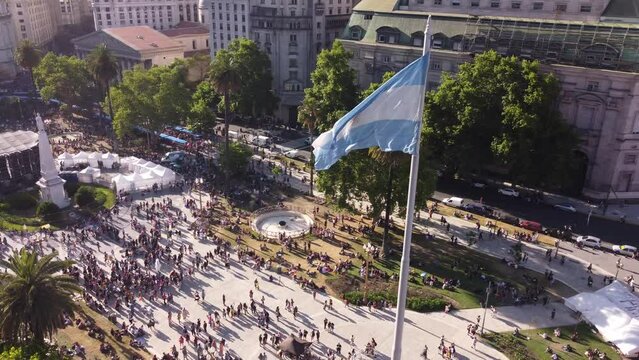 Drone flying around Argentinian flag waving in Plaza de Mayo during march LGBT event pride parade in Buenos Aires city. Aerial orbiting