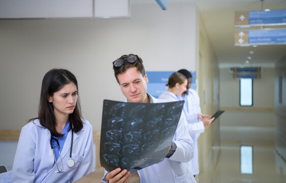Medical teacher and interns analyzing the x-ray results of the patient's brain. before major surgery in the operating room
