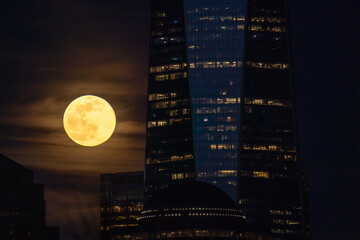 Full moon is rising behind skyscrapers in New York. Majestic view during full moon in city.