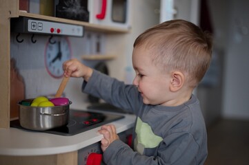 Cute little toddler playing with toy kitchen set
