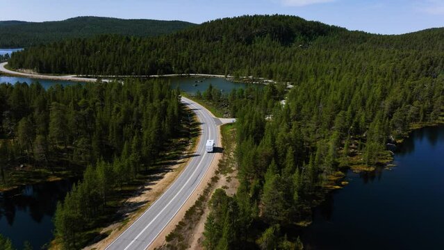 Aerial view following a camper driving polar road, summer day in Inari, Finland