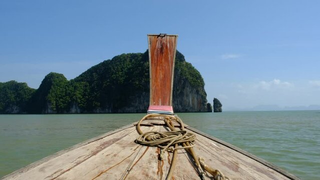 Shot of the front of a modest wooden boat sailing through Thailand's tropical waters.