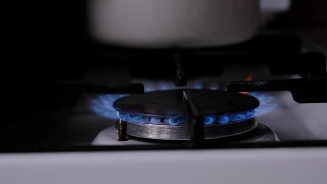 Ignition of the gas burner on the stove in the kitchen. Use of natural resources, economy, cooking on fire. Close-up
