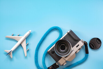 Flat lay of camera with blue color camera strap and mini model airplane on blue background , minimal style with copy space
