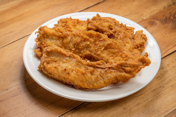 Fried chicken on white plate on wooden background.