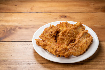 Fried chicken on white plate on wooden background.