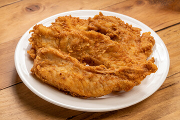 Fried chicken on white plate on wooden background.