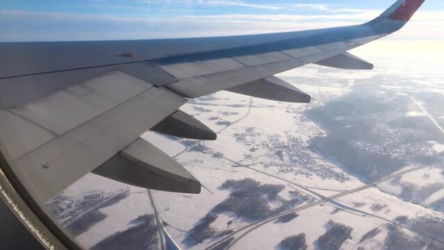 View from an airplane window. Plane flying over a snow-covered city. The concept of traveling by aircraft.