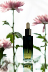 Cosmetic oil bottle with blurred chrysantemums