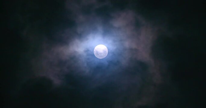 Full moon at night with clouds passing by.
