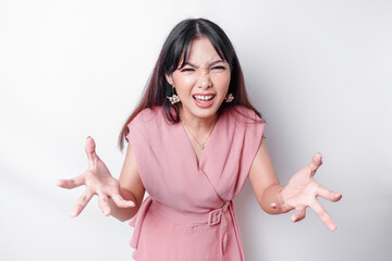 A dissatisfied young Asian woman looks at the camera posing on a white background, disgruntled girl...
