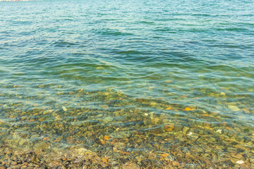 Sea stones in the sea water. Pebbles under water. The view from the top. Nautical background. Clean sea water. Transparent sea.