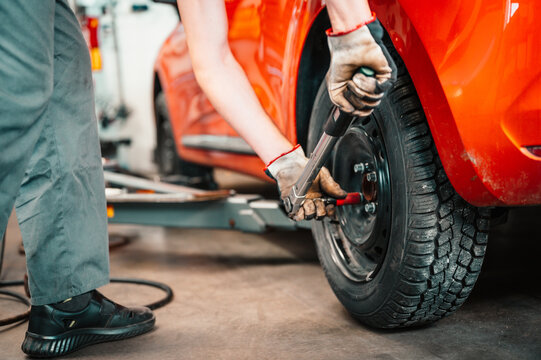 Car mechanic  changing wheel alloy tire. Working in garage.  Car service. Process of checking the condition of  tires replaced at a service center. Automobile industry.