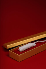 Women's hygienic tampon in a golden gift box on a red background.