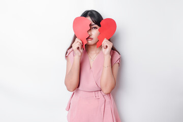 Beautiful young Asian woman expressed her sadness while holding broken heart isolated on white background