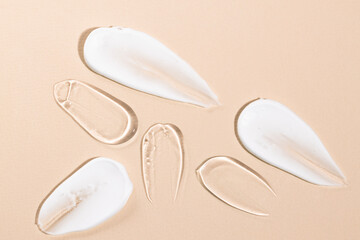 Samples of cosmetic textures in white and transparent color on a beige background top view. Body cream and peptide, care serum.