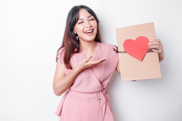 Beautiful young Asian woman dressed in pink blouse holding gift box red heart, Valentine's Day concept.