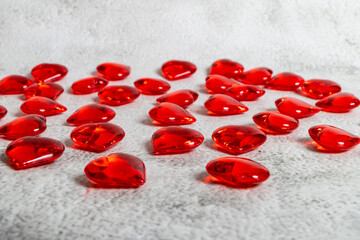 Red glass hearts on the light rustic background.
