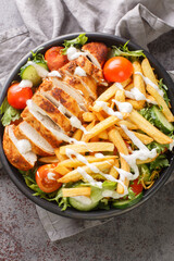 Homemade Pittsburgh Salad with french Fries and grilled chicken closeup on the bowl on the table. Vertical top view from above