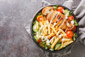 Warm Pittsburgh salad with chicken breast, french fries, vegetables, cheese and lettuce close-up in...