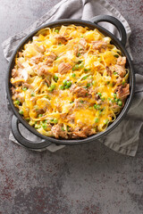 Obraz na płótnie Canvas Canned Tuna casserole with pasta, green peas, mushrooms and cheddar cheese close-up in a baking dish on the table. Vertical top view from above