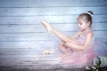 Little girl ballerina. Ballerina in a tutu. The girl is sitting at the window. Thoughtful girl ballerina. Little beautiful girl. Girl in pointe shoes.