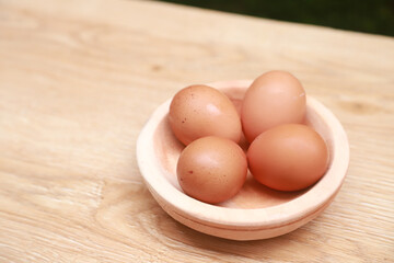 a few chicken eggs are placed in a wooden bowl