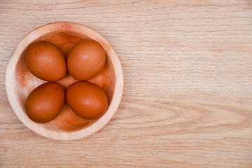 a few chicken eggs are placed in a wooden bowl