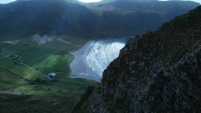 Aerial revealing shot of idyllic landscape and Hoddevik beach in Norway with mountains in backdrop - Top down view 