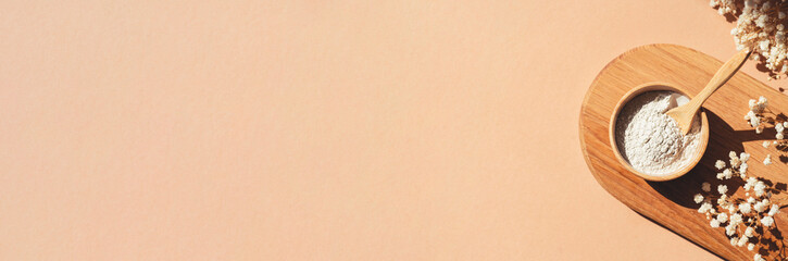 Wooden bowl with a spoon filled with white bath sea salt. Beauty treatment for spa and wellness on beige background.