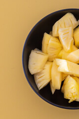 Pineapple chunks, Pineapple slices, Tasty canned pineapple pieces in a bowl on yellow table, copy space, Diet fruit, tropical fruit