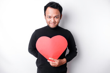 A portrait of a happy Asian man wearing a black shirt, holding a red heart-shaped paper isolated by white background