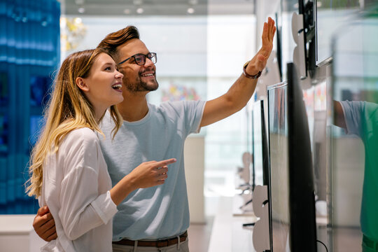 Portrait of happy couple shopping in a tech store. Technology people smart device concept