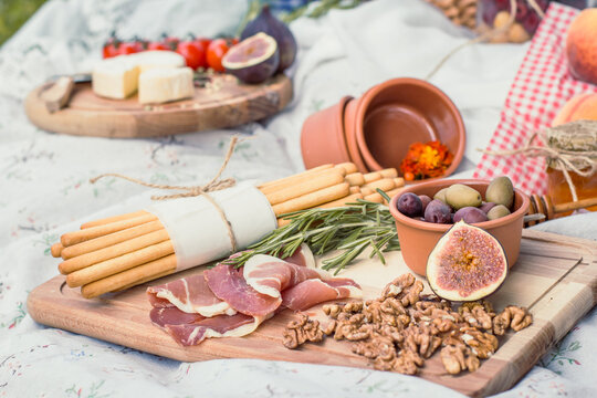Close up delicious picnic food on blanket concept photo. Romantic summer outing. Front view photography with blurred background. High quality picture for wallpaper, travel blog, magazine, article