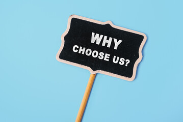 Why choose us - text on a small chalkboard on a blue background. Top view. Concept meaning list of...