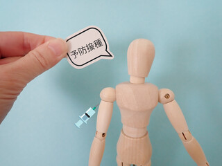 木製の人形に注射、吹き出しに予防接種の単語
