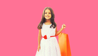 Portrait of little girl child with shopping bags on pink background