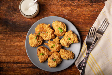 Cauliflower wings food. Pieces of flour-fried cauliflower with vegan sauces on a plate. Wooden background. Vegetarian food.