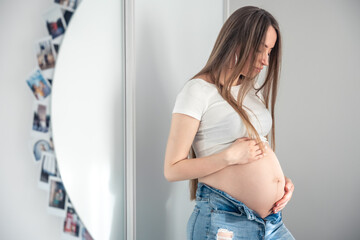 Attractive young pregnant woman in mirror reflection at home.