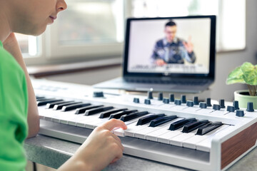 Fototapeta na wymiar A girl learns to play the piano with a teacher online, remote learning music.