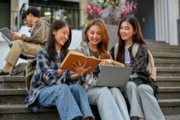 Group of charming Asian female college students sitting on street stairs, discussing their school project