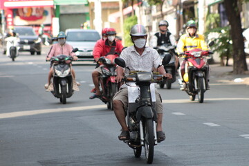 People ride a motorbike in Vietnam in traffic on a normal day. 