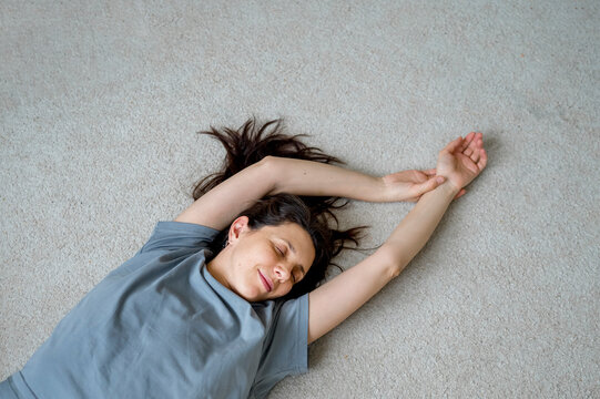 Woman with eyes closed lying on carpet at home