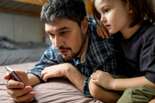Man sharing smart phone with son at home