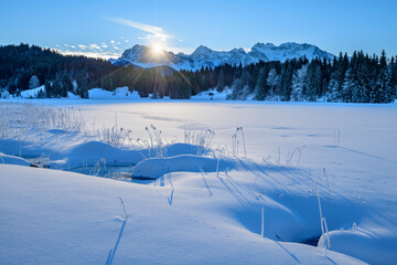 Germany, Bavaria, Sun rising over snow-covered lake in Bavarian Alps