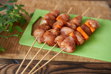 Raw chicken kebabs with vegetables on wooden skewers, close-up. Preparing to cook dinner on the grill.