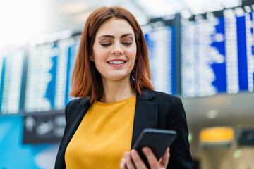 Smiling businesswoman using smart phone at airport